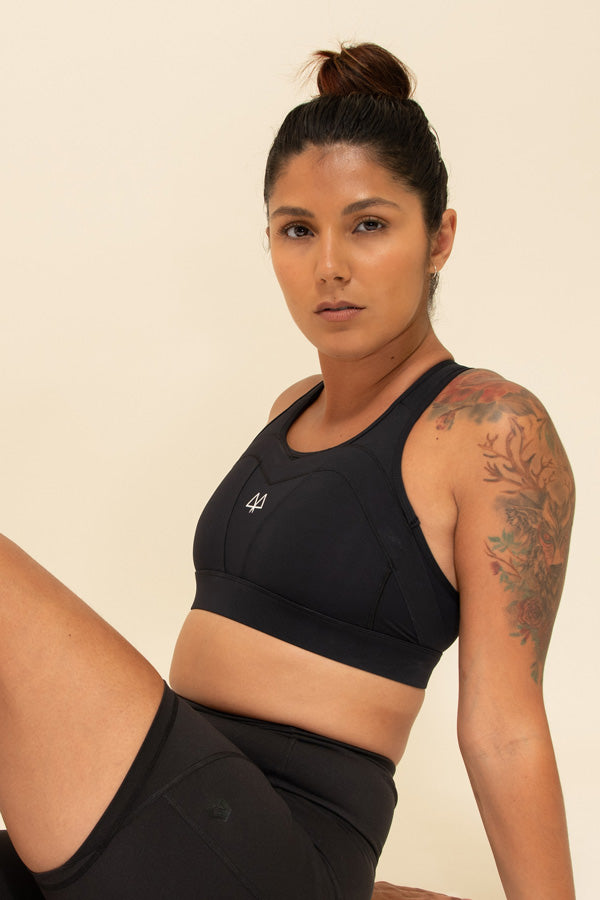 Woman sitting down wearing a supportive Black Sports Bra and Black Shorts.